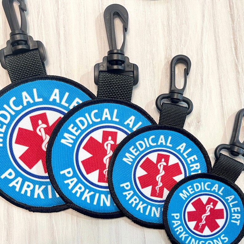 May include: Four blue and red medical alert keychains with black lanyards. The keychains have the text "Medical Alert Parking" and a red medical symbol.