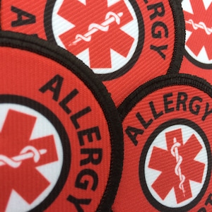 May include: Red and white allergy alert patches with a black border and the word "ALLERGY" printed in black. The patches feature a red star of life symbol with a white snake wrapped around it.