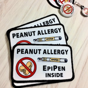 May include: Three white patches with black borders and the text "Peanut Allergy" and a red circle with a diagonal line through it and a picture of peanuts. The bottom patch also has the text "EpiPen Inside" and a picture of an EpiPen.