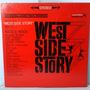 May include: A red vinyl record album cover with the title "West Side Story" in black text. The album features the names of the actors and the director, Robert Wise. The album is a Columbia Masterworks release.