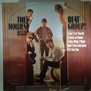 May include: A vintage vinyl record album cover featuring a band called "The Hollies" with the title "Beat Group!" and a list of songs including "I Can't Let You Go", "A Taste of Honey", "I Take What I Want", "Don't You Even Care", and "Fifi The Flea". The cover features a photo of the band members standing on a beach.