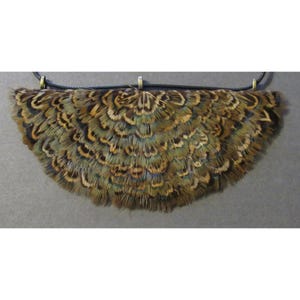 May include: A necklace featuring a fan-shaped pendant made of brown, tan, and blue feathers. The feathers are attached to a black cord with gold-colored metal accents. The pendant is approximately 6 inches wide.
