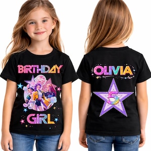 Puede incluir: Camiseta negra con un gráfico colorido de "BIRTHDAY GIRL" con personajes de dibujos animados y estrellas. La parte trasera de la camiseta muestra "OLIVIA" y una estrella con el número "5".
