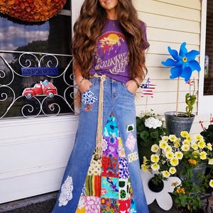 Puede incluir: Una mujer con una camiseta morada con un gráfico y una falda larga de mezclilla con retazos coloridos. La falda tiene un detalle de encaje blanco. La camiseta dice "Johnny Cash".