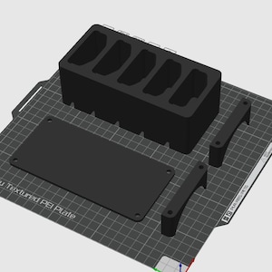 Pode incluir: Um organizador preto impresso em 3D com múltiplos compartimentos, uma base retangular e duas alças curvas. O organizador está sobre uma placa PEI texturizada. O texto "Bambu Textured PEI Plate" é visível.