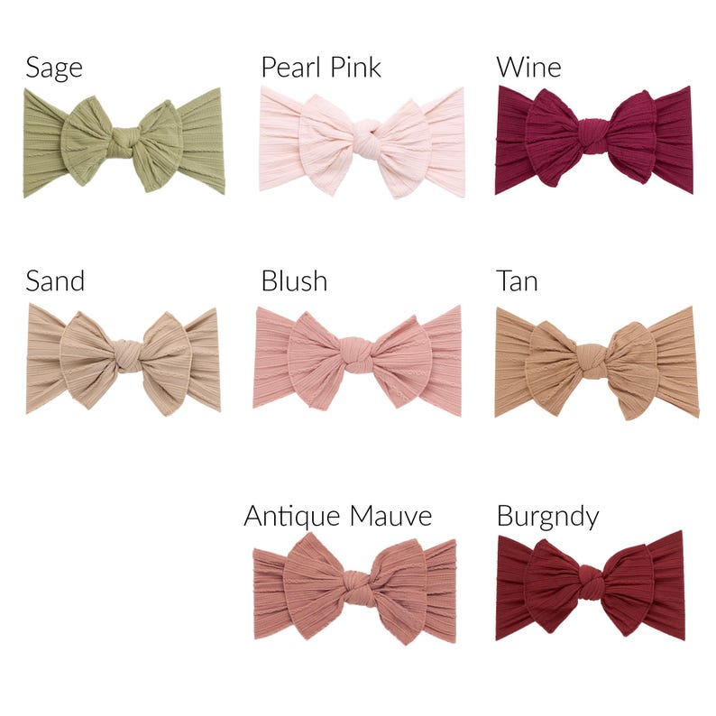 May include: A collection of eight ribbed fabric headbands in various colors, including sage, pearl pink, wine, sand, blush, tan, antique mauve, and burgundy. Each headband features a large bow.