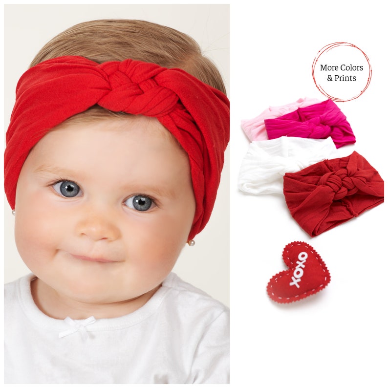 May include: A red knotted headband is worn by a baby with blue eyes and a white shirt. Additional headbands in pink and white are displayed, along with a red heart-shaped decoration with "xoxo" text. The image also includes the text "More Colors & Prints".