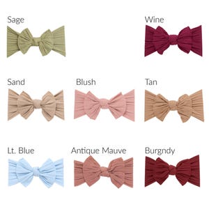May include: A collection of eight ribbed fabric headbands, each featuring a central knotted bow design. The colors displayed are labeled as Sage, Wine, Sand, Blush, Tan, Lt. Blue, Antique Mauve, and Burgndy, arranged in a grid format.