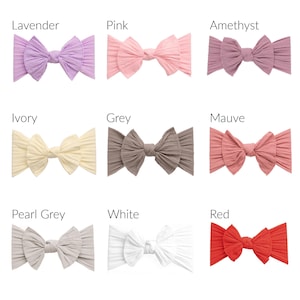 May include: A collection of nine ribbed fabric headbands with knotted bow centers, displayed in a grid. Colors include lavender, pink, amethyst, ivory, grey, mauve, pearl grey, white, and red, each labeled with its corresponding color name.