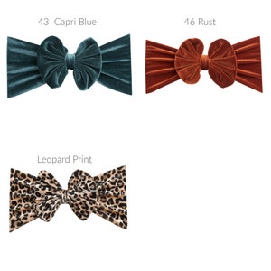May include: Three velvet headbands in different colors and patterns. The first headband is teal blue, the second is rust orange, and the third is a leopard print.
