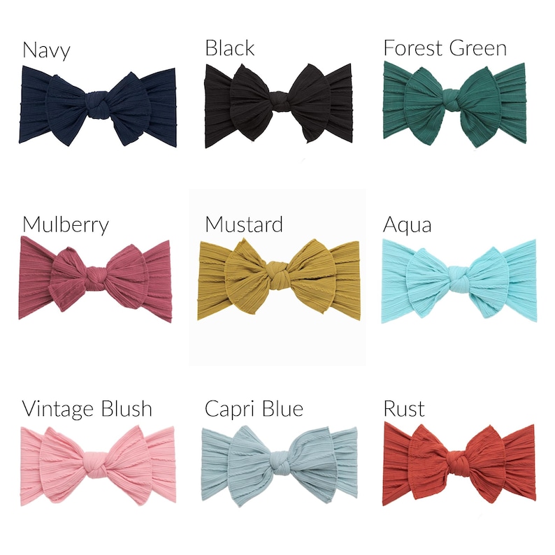 May include: A collection of nine ribbed fabric headbands with knotted bows, displayed in a grid. Colors include navy, black, forest green, mulberry, mustard, aqua, vintage blush, capri blue, and rust, each labeled with its respective color name.