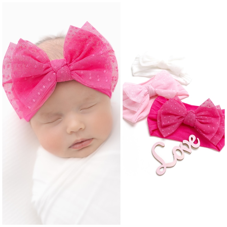 Pu&ograve; includere: Tre fasce per capelli in tulle a pois rosa e bianco con fiocchi. Le fasce sono impilate con il fiocco pi&ugrave; grande in cima. La parola "Love" &egrave; scritta in rosa su un cartello di legno.
