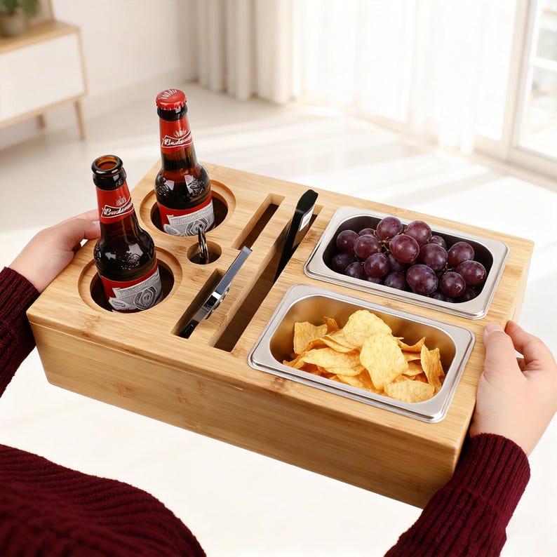 May include: A bamboo serving tray with two beer bottles, two stainless steel containers holding grapes and chips, and slots for utensils. The tray is designed for snacks and drinks.