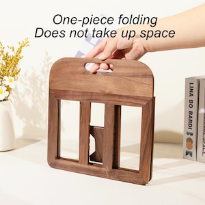 May include: A wooden, folding easel with a handle at the top. The easel is a warm brown color and has a rectangular frame with a series of vertical supports. The text "One-piece folding Does not take up space" is visible on the image.