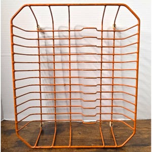 May include: A rectangular orange wire document tray featuring a grid pattern with multiple horizontal slots for organising papers. The metal structure has rounded corners and small white protective feet at each of the four bottom corners.
