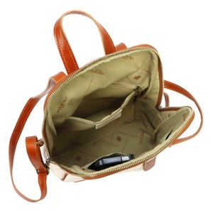 May include: Open view of a cream and brown leather backpack. The bag has a top handle and adjustable straps. The interior is beige with multiple pockets and a zipper closure. A black smartphone is visible inside the bag.