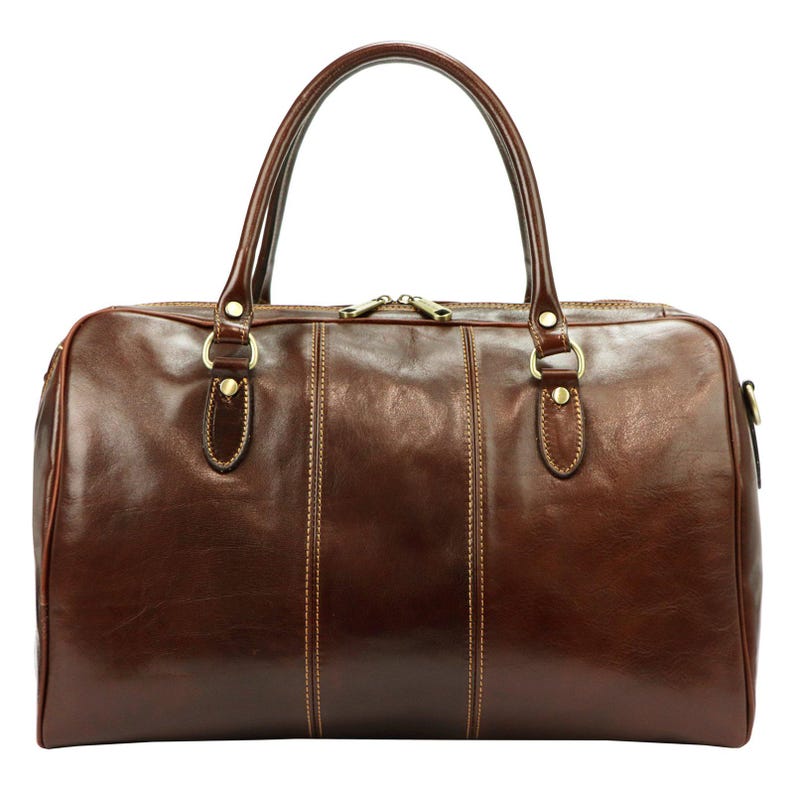 Puede incluir: Una bolsa de lona de cuero marr&oacute;n con dos asas superiores y un cierre de cremallera. La bolsa tiene forma rectangular con detalles de costura verticales y herrajes dorados. La bolsa est&aacute; dise&ntilde;ada para viajes.