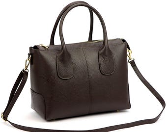 May include: A dark brown leather handbag with a textured finish. The bag has two top handles and a detachable shoulder strap. Gold-colored zippers and hardware add a touch of elegance to this structured satchel.