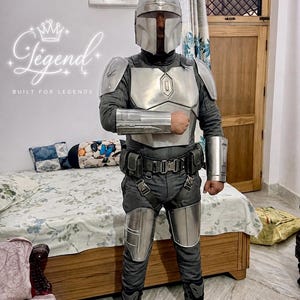 May include: A full-body costume resembling a character from a science fiction series. The costume features a silver helmet, chest plate, and arm guards over a dark gray jumpsuit. The text "Legend Built for Legends" is visible.