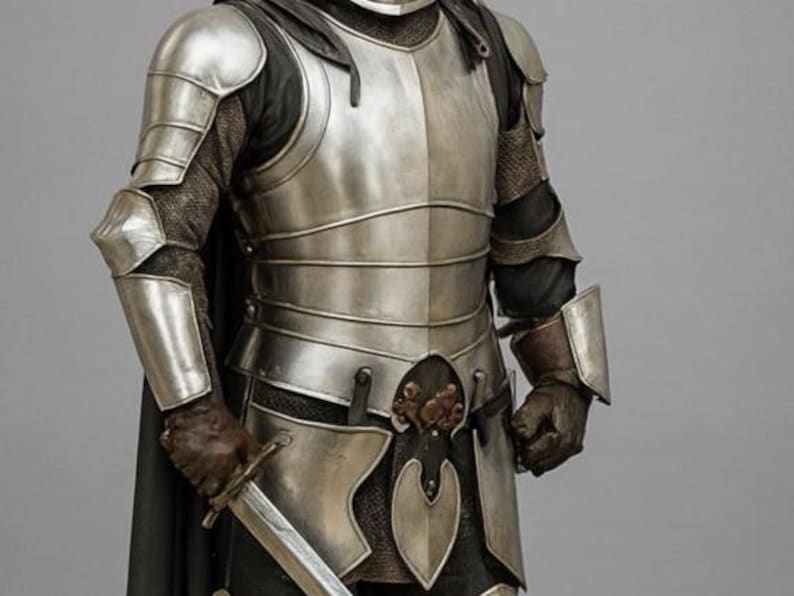 May include: Silver-coloured medieval armour with articulated plates, including chest, shoulder, and arm protection. The armour is worn over a dark garment, with chainmail visible at the sleeves. A sword is held at the waist, and the gloves are brown.