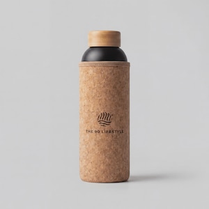 May include: A cylindrical water bottle featuring a black upper section, a light brown wooden cap, and a textured cork sleeve covering the lower body. The cork sleeve displays a circular logo and the text THE 90 LIFESTYLE printed in black ink.