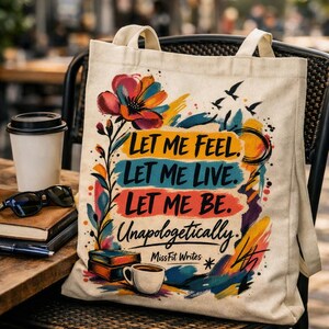 May include: A beige canvas tote bag featuring a colorful watercolor-style graphic with a large flower, books, and a coffee cup. The text reads: LET ME FEEL. LET ME LIVE. LET ME BE. Unapologetically. MissFit Writes. The design includes abstract brushstrokes.