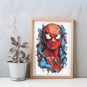 Pode incluir: Obra de arte emoldurada com um retrato estilizado do Homem-Aranha. A imagem mostra o icónico traje vermelho e azul do super-herói, com uma representação detalhada da sua máscara e fato. A obra é exibida numa moldura de madeira castanha clara.