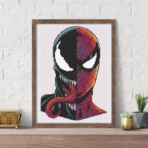 May include: Framed cross-stitch art featuring a split design of Venom and Spider-Man. The artwork showcases the characters' faces, with Venom's black and Spider-Man's red and black colors. The piece is displayed in a wooden frame.