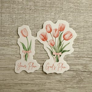 May include: Two stickers featuring watercolor illustrations of tulips. One sticker has a single tulip, the other has a bouquet. Both have pink bows and the phrases "Your Plan" and "God's Plan" in pink script.