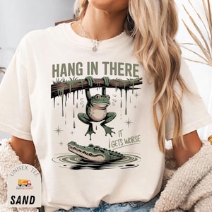 Hang In There It Gets Worse Shirt | Funny Sarcastic Frog Tee | Retro Humor Graphic T-Shirt | Trendy Quote Shirt for Women Gift