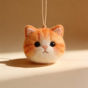 Può includere: Ornamento a forma di gatto fatto a mano in feltro arancione e bianco, con occhi neri e naso rosa. La testa rotonda ha un cordino per appenderlo. Una graziosa decorazione artigianale.