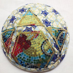 Könnte beinhalten: Eine weiße Kippa mit einem blauen und goldenen geometrischen Muster und einem großen gestickten Davidstern in der Mitte.