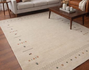 May include: Beige area rug with a geometric pattern in brown, black, and green. The rug is rectangular and placed on a dark wood floor. The rug is in a living room setting with a sofa, chairs, and a coffee table.