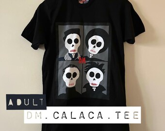 Peut inclure: T-shirt noir avec un motif à quatre panneaux de visages de crânes stylisés aux lèvres rouges. Le t-shirt comprend le texte "ADULT DM. CALACA. TEE". Les crânes ont différentes coiffures et détails vestimentaires.