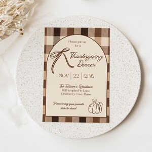 May include: Thanksgiving dinner invitation card with a brown and beige plaid border. The invitation includes the text "Please join us for a Thanksgiving Dinner" and the date, November 22, 12 PM. The card also includes the address and a request to bring a dish.