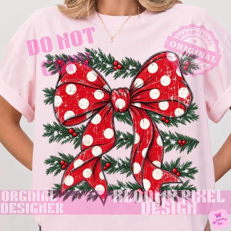 May include: A light pink t-shirt featuring a large red bow with white polka dots, layered over a background of green pine branches with small red berries. The design has a distressed, vintage texture throughout the bow and the foliage.