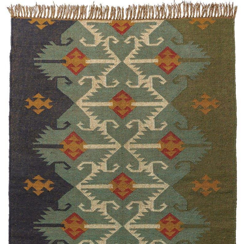 May include: A rectangular rug with a geometric pattern in shades of blue, green, and beige. The design features repeating shapes with orange accents. The rug has a fringed edge and is suitable for home decor.