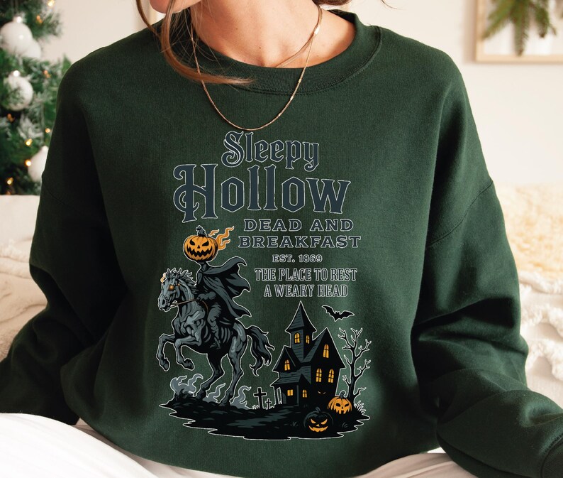 A green sweatshirt with a Halloween-themed graphic design featuring a spooky horse, a castle, and jack-o-lanterns.