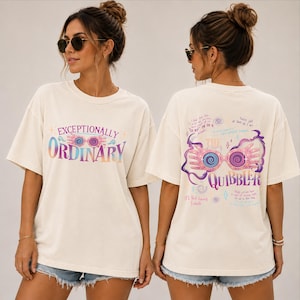 May include: An off-white short-sleeve t-shirt featuring a front graphic with the text "EXCEPTIONALLY ORDINARY" and pink spectacles. The back graphic displays "THE QUIBBLER" with pink spectacles, purple swirls, and handwritten-style text.
