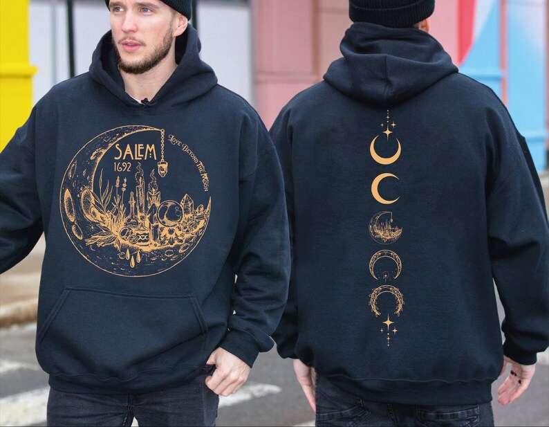 A man wearing a black hoodie with a gold design on the front and back.