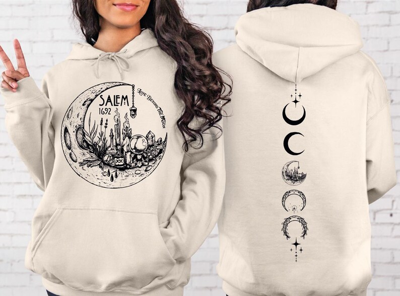 A woman wearing a white hoodie with a graphic design on the front and a back featuring a series of black symbols and images.