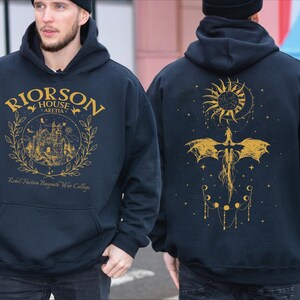 a man wearing a black hoodie with a yellow dragon on it
