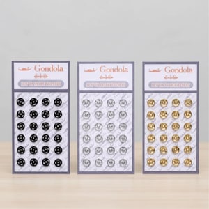 May include: Three packs of sew-on snap fasteners in black, silver, and gold. Each card displays a grid of snaps, with the brand name "Gondola" and the text "Sew On Snap Fasteners" printed on the top.
