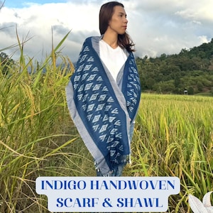 Peut inclure: Écharpe et châle indigo tissés à la main, bleus et blancs, avec un motif géométrique. L'écharpe a une bordure à franges et est drapée sur une personne. Le texte "INDIGO HANDWOVEN SCARF & SHAWL" est affiché en bas de l'image.