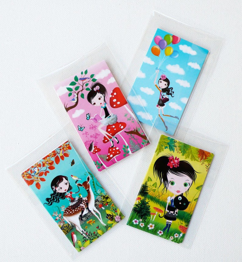 May include: Four colorful cards featuring illustrations of girls in different settings. The first card shows a girl with black hair sitting on a red mushroom in a forest. The second card shows a girl with black hair holding balloons in a blue sky. The third card shows a girl with black hair riding a deer in a forest. The fourth card shows a girl with black hair holding a black cat in a forest.