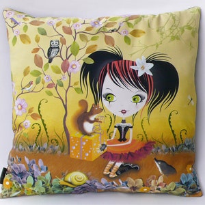 Peut inclure: Un coussin jaune et brun avec une fille de dessin animé aux cheveux roux et noirs, aux yeux verts et à une robe noire et blanche. La fille tient une boîte cadeau et un écureuil est assis sur le dessus de la boîte. L'arrière-plan est une scène de forêt jaune et verte avec des fleurs et des arbres.