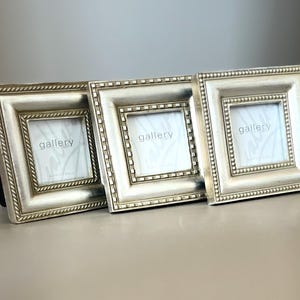 May include: Three square silver-toned picture frames arranged in a row. Each frame features a wide border with a beaded or rope-like texture and contains a white insert with the word gallery printed in the center in a light gray font.