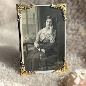 Rechthoekige goudkleurige metalen sierlijke fotolijst in retro-victoriaanse stijl.