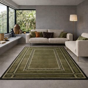 Olive green modern area rug with geometric border design placed in a minimalist living room with beige sofa and natural light