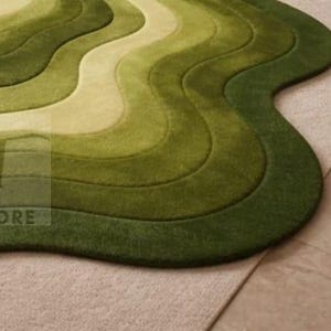 Topographic layered green area rug shown in a spacious classical interior. Wavy organic shape with multiple contour layers in deep and light green tones, resembling terrain elevation. Plush tufted texture, modern artistic floor decor for living rooms or luxury spaces.